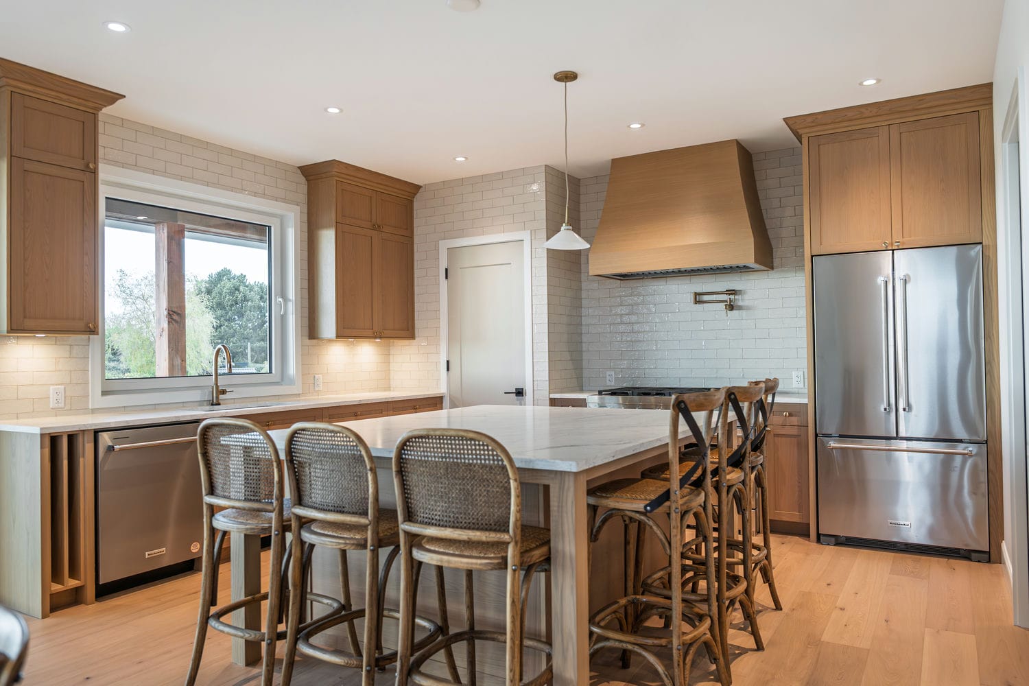 Delta farmhouse kitchen in stained oak with a wood range hood and a veined stone island