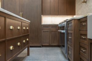 Brass cup pulls on the island drawer fronts, with a square furniture leg and terrazzo floor